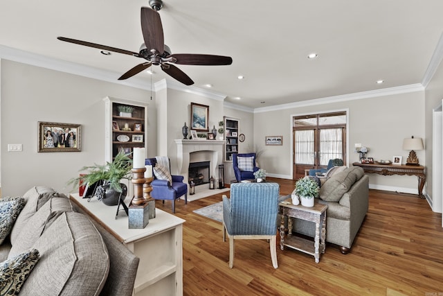 living area with light wood-style floors, baseboards, ornamental molding, and a fireplace with flush hearth