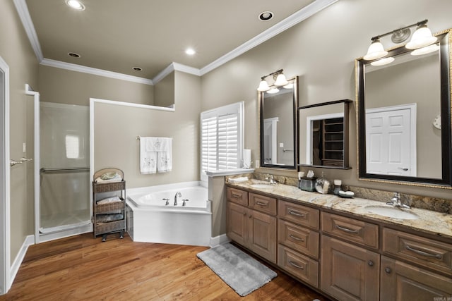 full bathroom featuring a garden tub, crown molding, double vanity, a sink, and wood finished floors