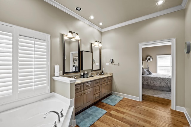 ensuite bathroom featuring a sink, a garden tub, crown molding, and wood finished floors