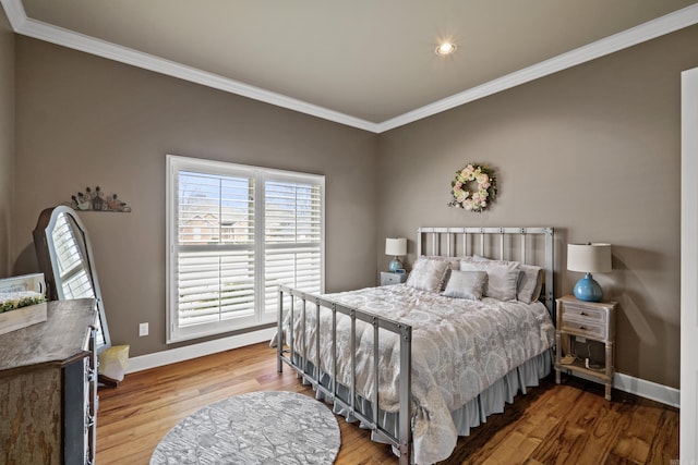 bedroom featuring baseboards, wood finished floors, and ornamental molding