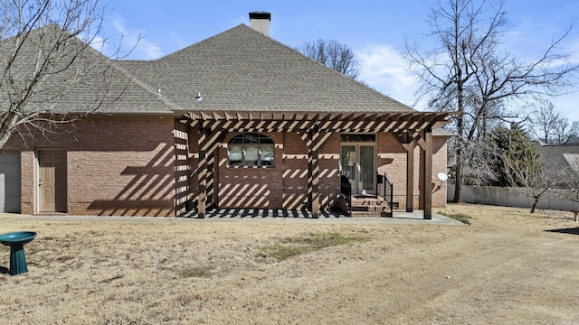 rear view of house with a shingled roof, a chimney, a pergola, and brick siding