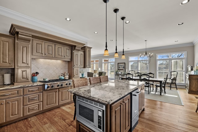 kitchen featuring light wood-type flooring, backsplash, stainless steel appliances, and a wealth of natural light