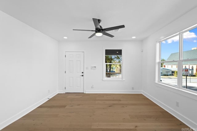 spare room with recessed lighting, wood finished floors, a wealth of natural light, and baseboards