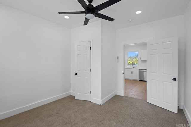 unfurnished bedroom featuring recessed lighting, light carpet, a sink, and baseboards