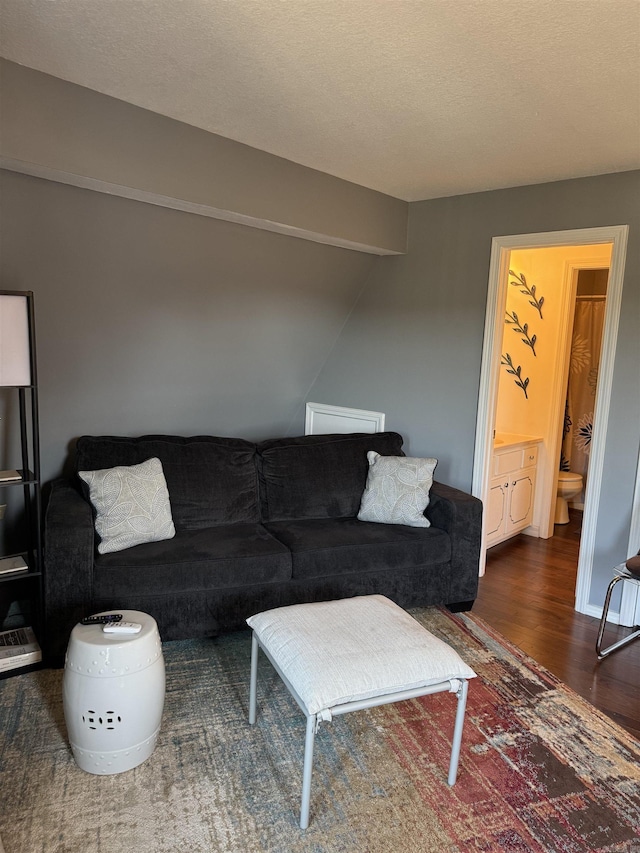 living room with a textured ceiling, vaulted ceiling, and wood finished floors