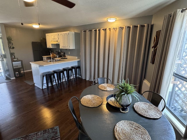 dining space featuring dark wood-style floors, ceiling fan, and baseboards