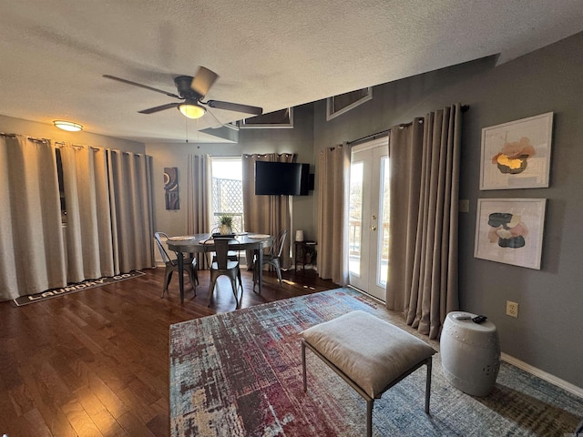 dining room featuring dark wood-style floors, a textured ceiling, baseboards, and a ceiling fan