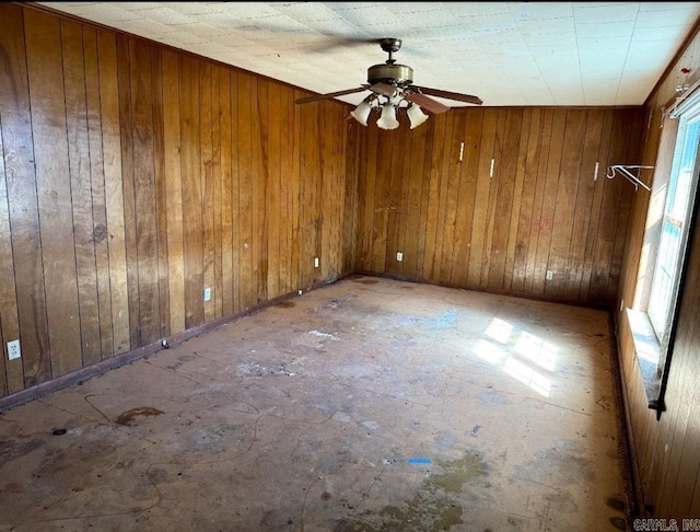 spare room with ceiling fan and wood walls