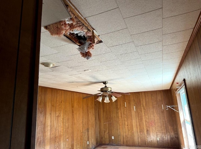 spare room with ceiling fan and wooden walls