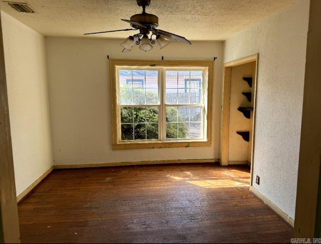 unfurnished room with visible vents, a textured wall, a textured ceiling, and hardwood / wood-style flooring