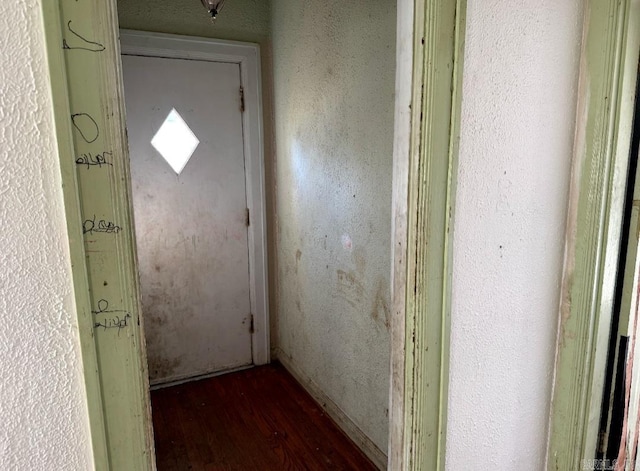 doorway with wood finished floors and a textured wall