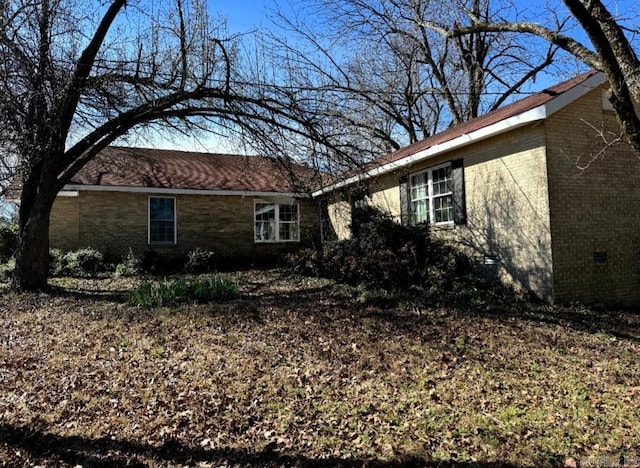 view of side of home with brick siding and crawl space