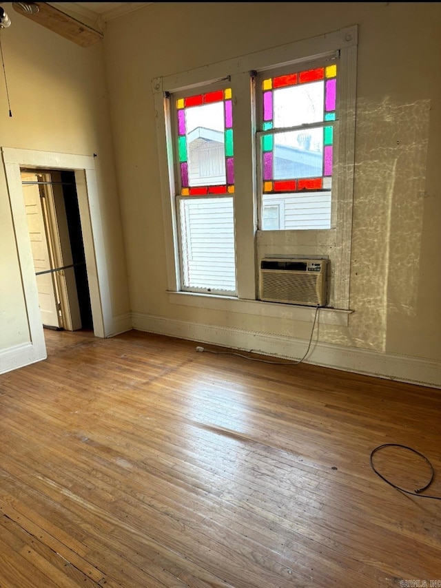 spare room with ceiling fan, cooling unit, wood finished floors, and baseboards