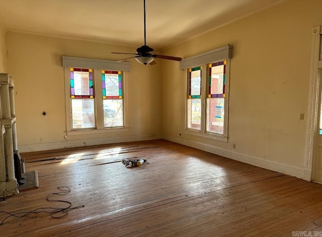 spare room featuring wood-type flooring, crown molding, baseboards, and ceiling fan