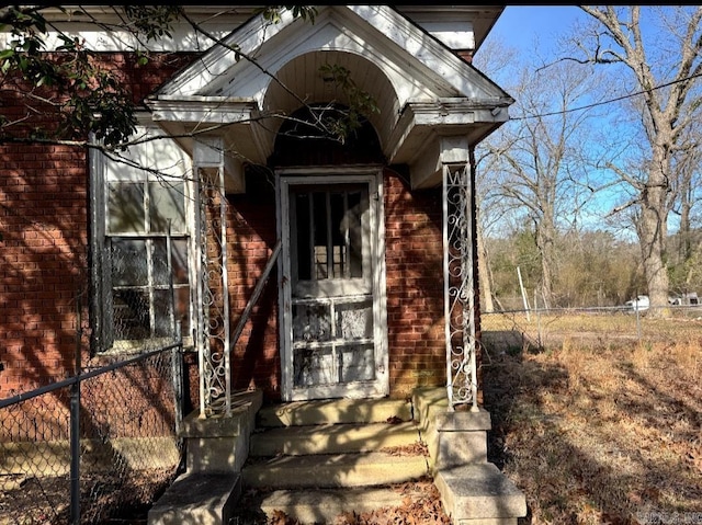 property entrance featuring brick siding and fence