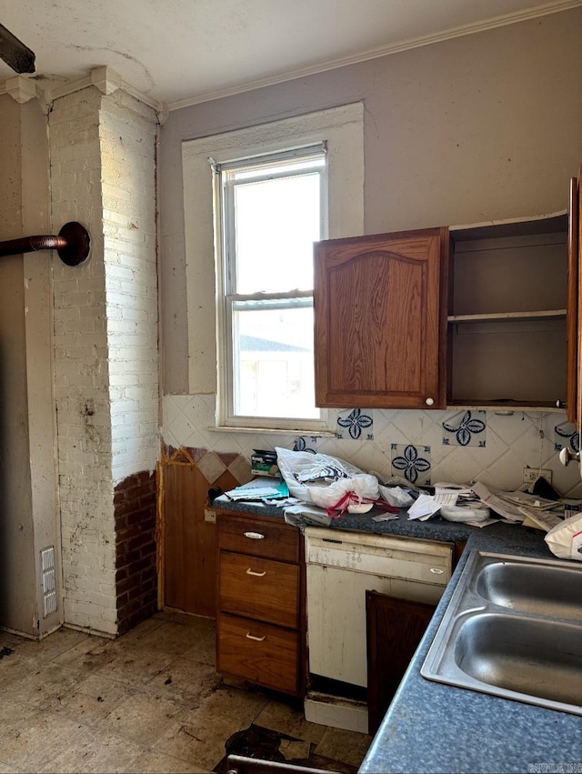 kitchen with brick wall, a sink, tasteful backsplash, brown cabinetry, and crown molding