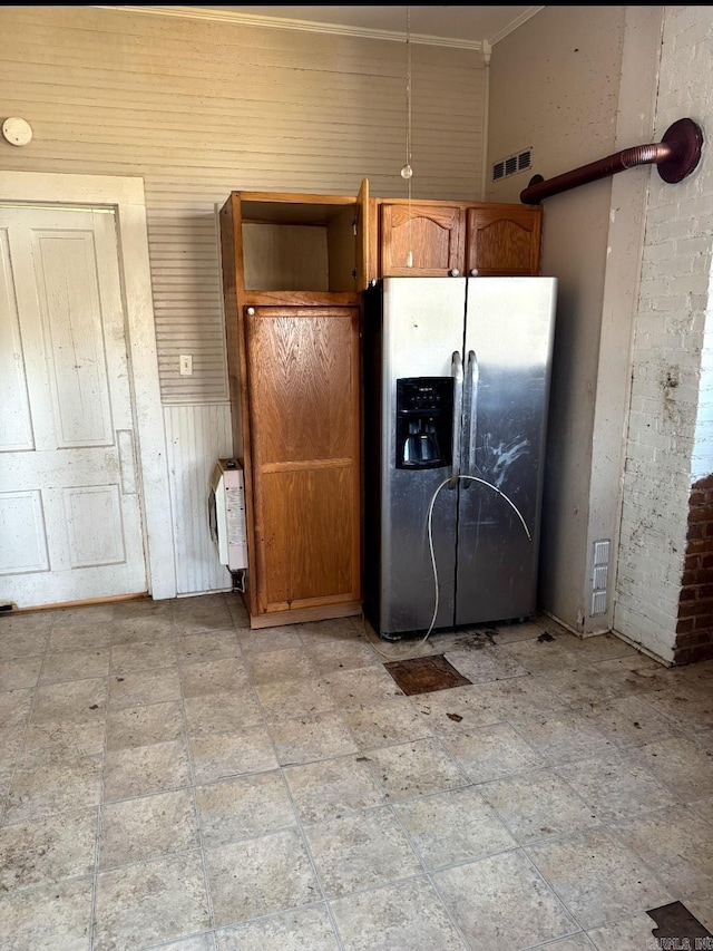 kitchen with a wainscoted wall, visible vents, ornamental molding, brown cabinets, and stainless steel fridge