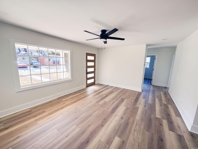 empty room with ceiling fan, baseboards, and wood finished floors