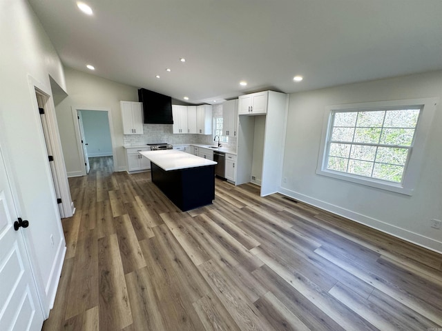 kitchen featuring a center island, light countertops, backsplash, appliances with stainless steel finishes, and a sink