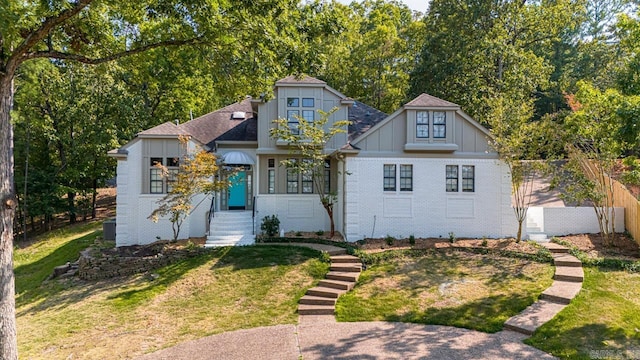 view of front of house with a front yard, fence, board and batten siding, and brick siding