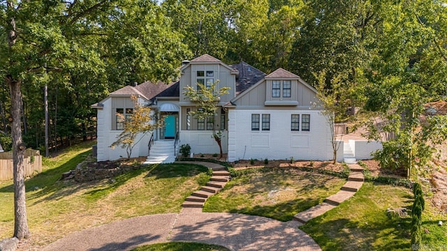 view of front of house with fence, a front lawn, board and batten siding, and brick siding