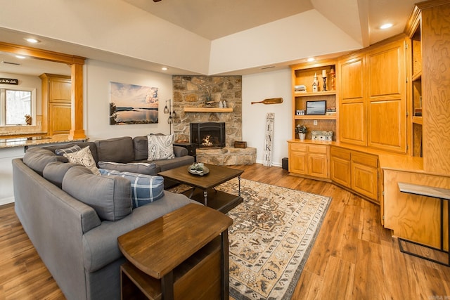 living room featuring decorative columns, built in shelves, light wood-style floors, a fireplace, and recessed lighting