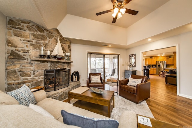 living room with visible vents, baseboards, a ceiling fan, light wood-style floors, and a fireplace