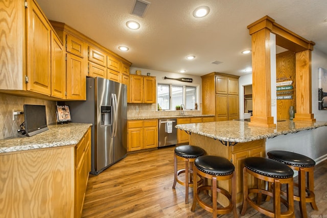 kitchen with a breakfast bar area, stainless steel appliances, visible vents, a sink, and a peninsula