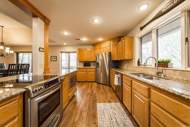 kitchen with light wood finished floors, appliances with stainless steel finishes, a sink, and a healthy amount of sunlight