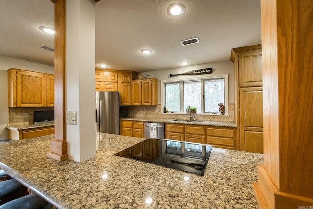 kitchen with light stone counters, a sink, visible vents, appliances with stainless steel finishes, and tasteful backsplash