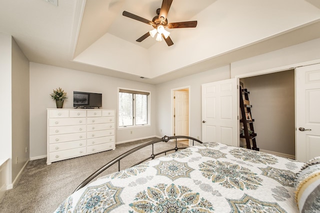 carpeted bedroom with ceiling fan, baseboards, and a raised ceiling