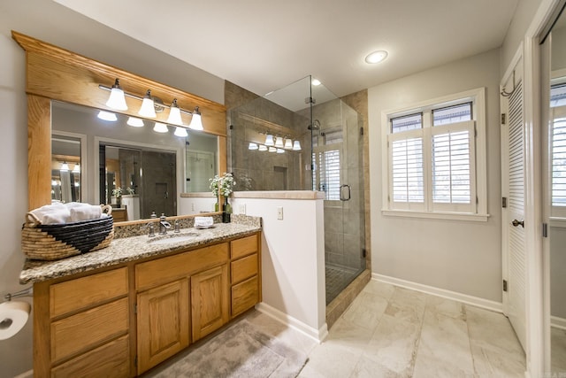 bathroom with baseboards, a shower stall, and vanity