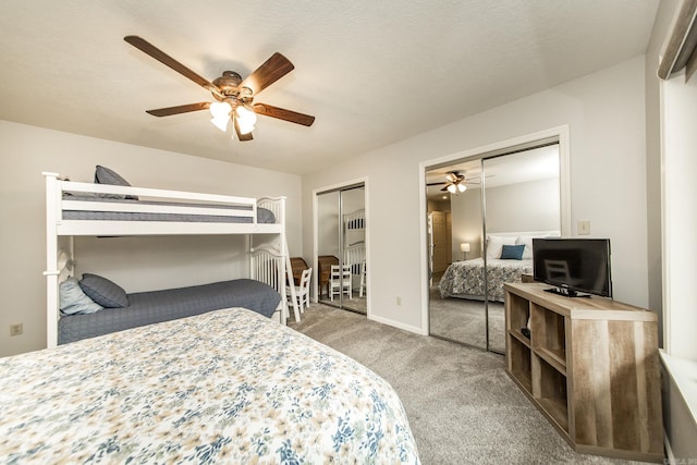 carpeted bedroom featuring baseboards, a ceiling fan, and two closets