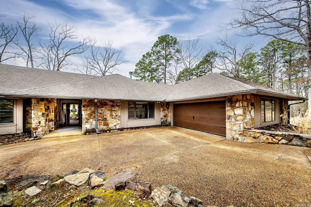 view of front of property with a garage, stone siding, roof with shingles, and concrete driveway