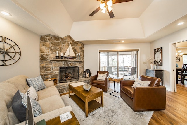 living room with visible vents, a ceiling fan, wood finished floors, vaulted ceiling, and a fireplace