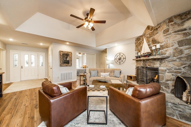 living area with a ceiling fan, visible vents, a fireplace, and wood finished floors