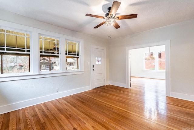 empty room with ceiling fan, baseboards, and wood finished floors