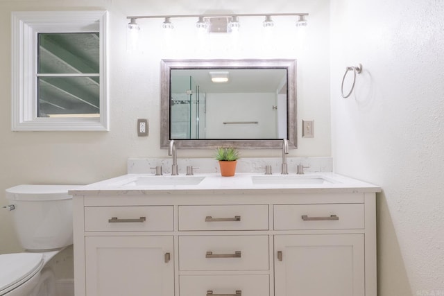 bathroom featuring double vanity, a sink, and toilet