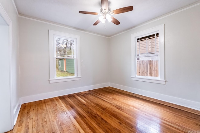 empty room with light wood finished floors, ornamental molding, and baseboards