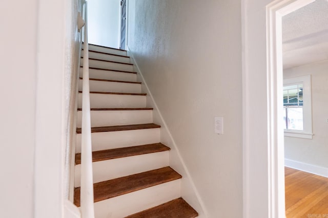 stairs with wood finished floors and baseboards