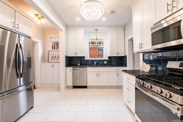 kitchen with visible vents, white cabinets, appliances with stainless steel finishes, backsplash, and dark countertops