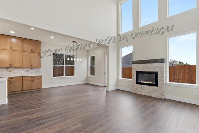 unfurnished living room with dark wood-style floors, a fireplace, and baseboards