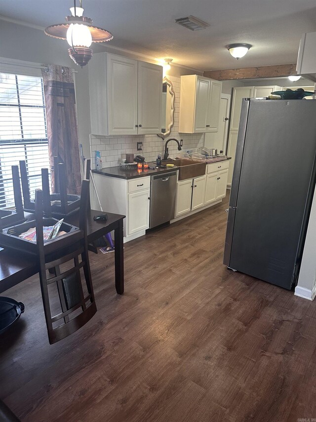 kitchen with appliances with stainless steel finishes, dark countertops, dark wood finished floors, and backsplash