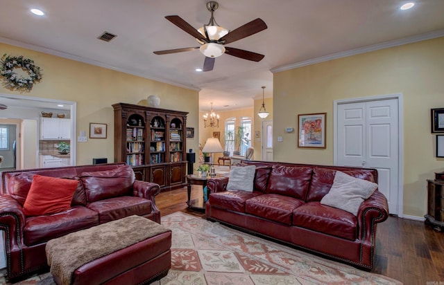 living area featuring ceiling fan with notable chandelier, light wood-style flooring, visible vents, and crown molding