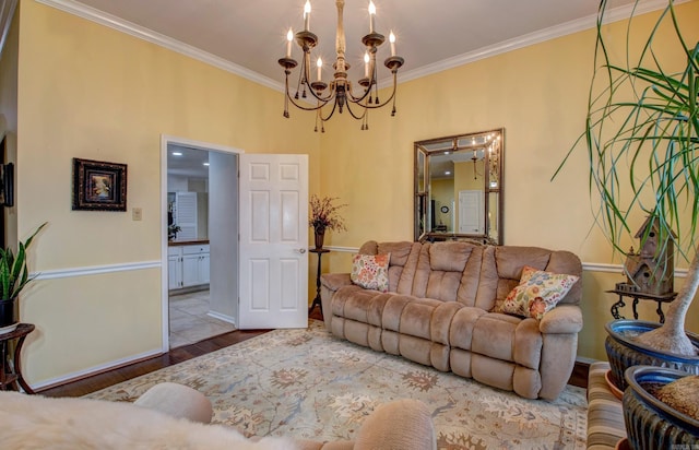 living room featuring ornamental molding, a notable chandelier, baseboards, and wood finished floors