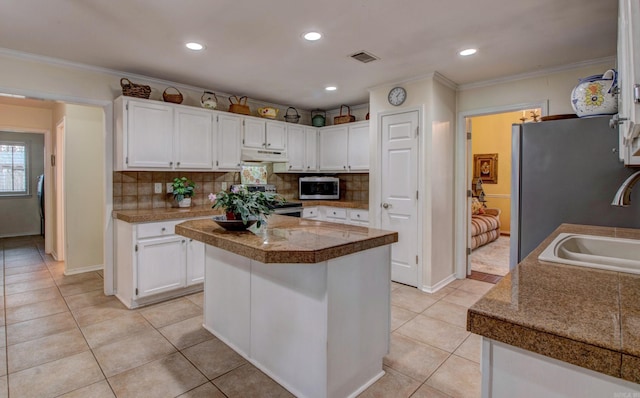 kitchen with stainless steel appliances, visible vents, white cabinetry, light tile patterned flooring, and under cabinet range hood