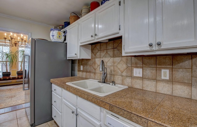 kitchen featuring crown molding, tile countertops, decorative backsplash, white cabinetry, and a sink