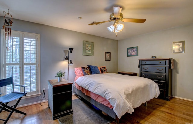 bedroom with light wood-style floors, multiple windows, baseboards, and a ceiling fan