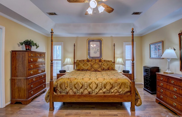 bedroom with a tray ceiling, visible vents, and wood finished floors