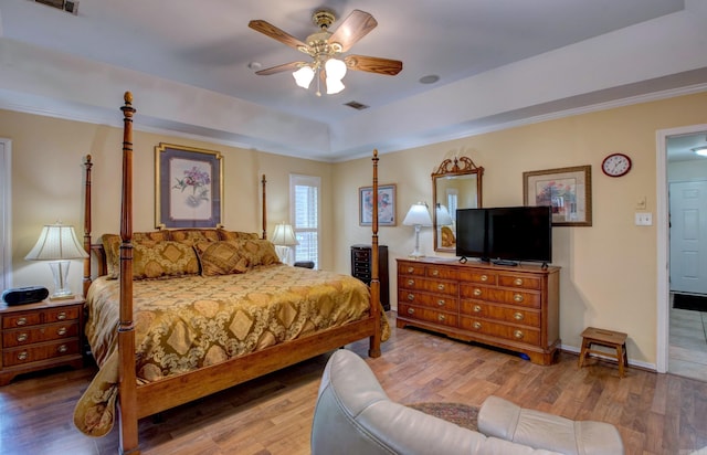 bedroom with baseboards, visible vents, a raised ceiling, and wood finished floors